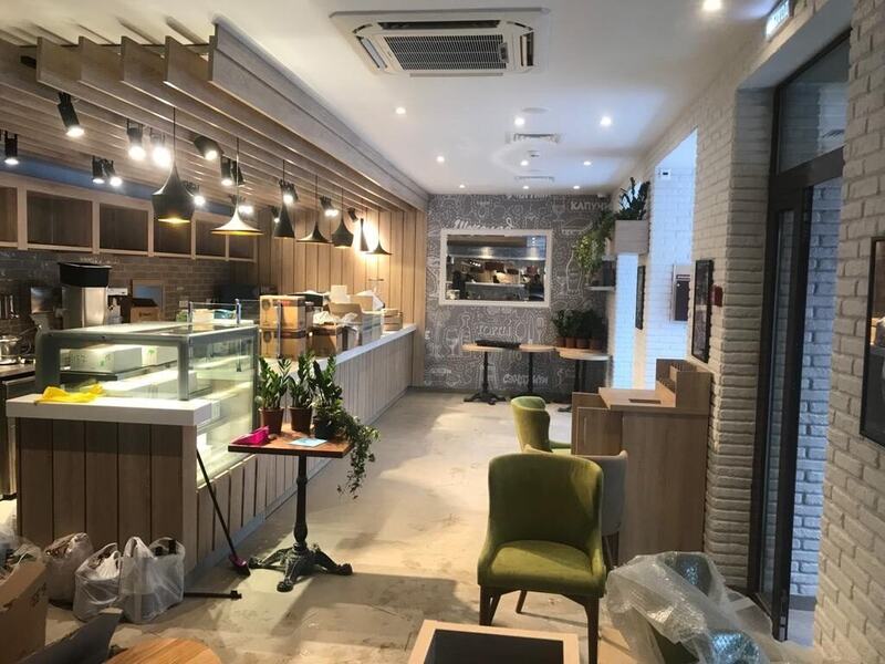 Café interior with wood-slat ceiling, pendant lights, and display counter