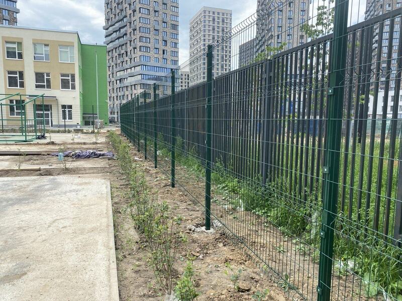 Long run of green welded-mesh panel fencing with new plantings