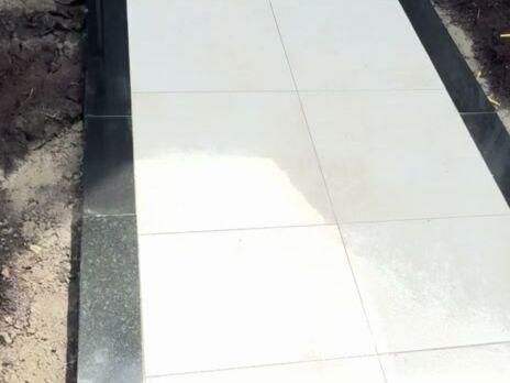 Light porcelain tile walkway framed by a black granite border