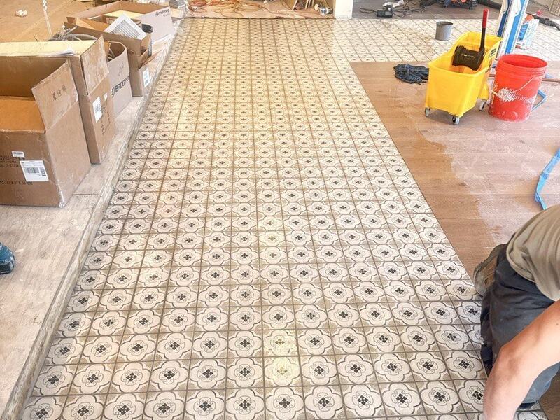 Finished patterned tile floor being sponged clean after grouting